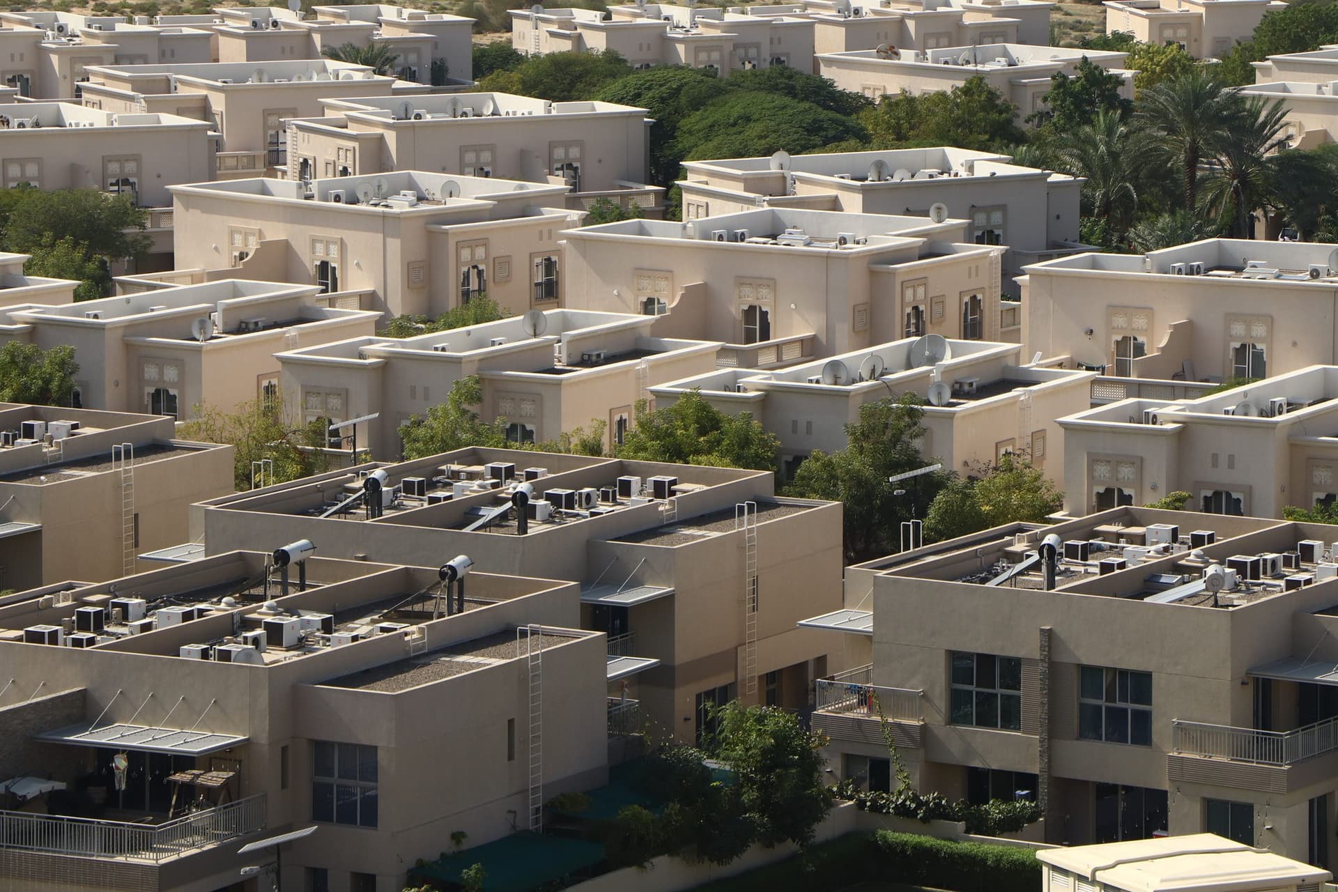 An aerial view of a villa community, with air-conditioning condenser units and solar water heaters on the flat roofs.