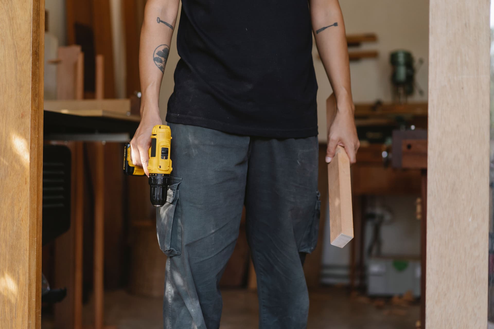 A cordless drill and a length of timber held in a joinery workshop.