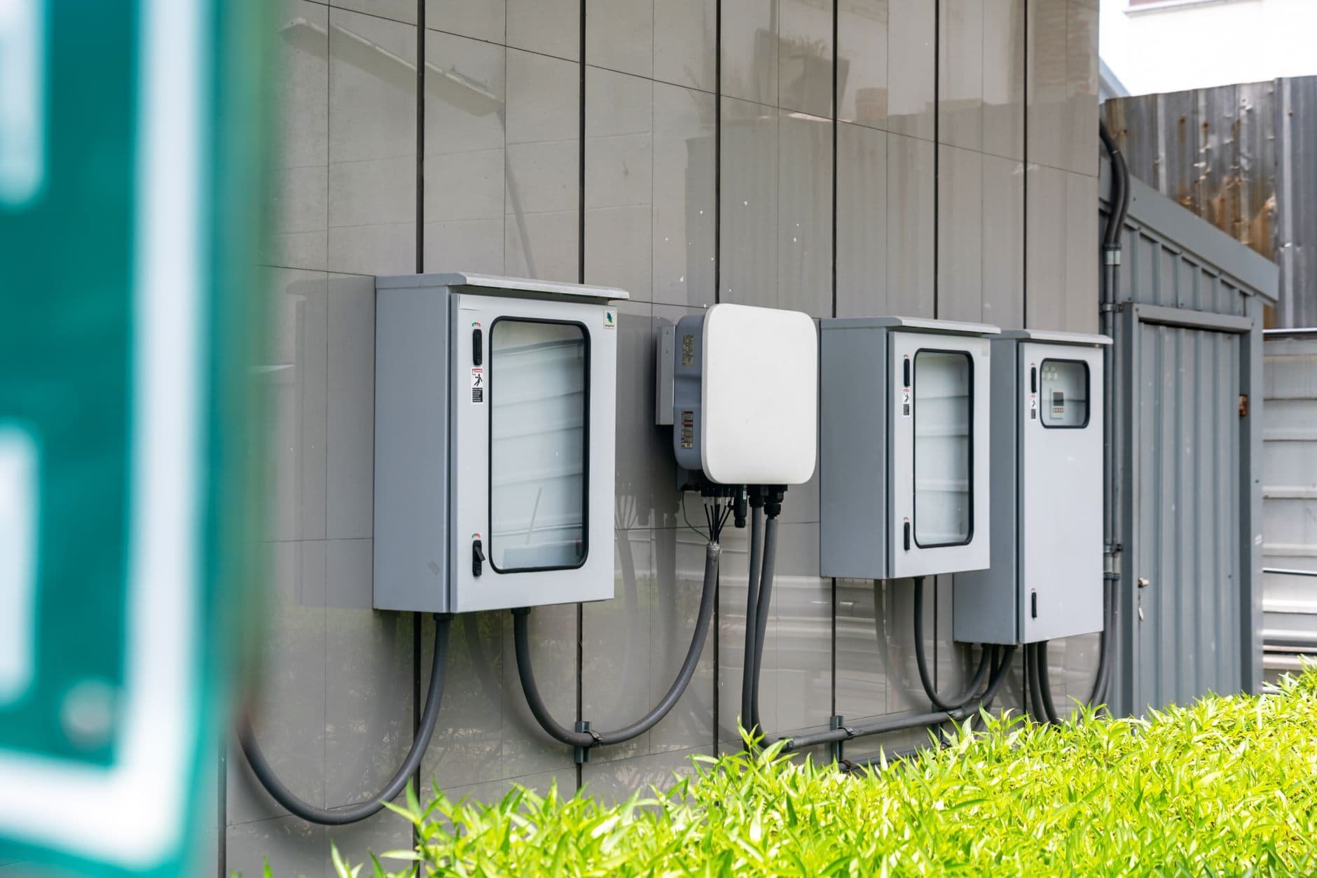 A row of wall-mounted electrical enclosures and an inverter unit, with conduit running between them.