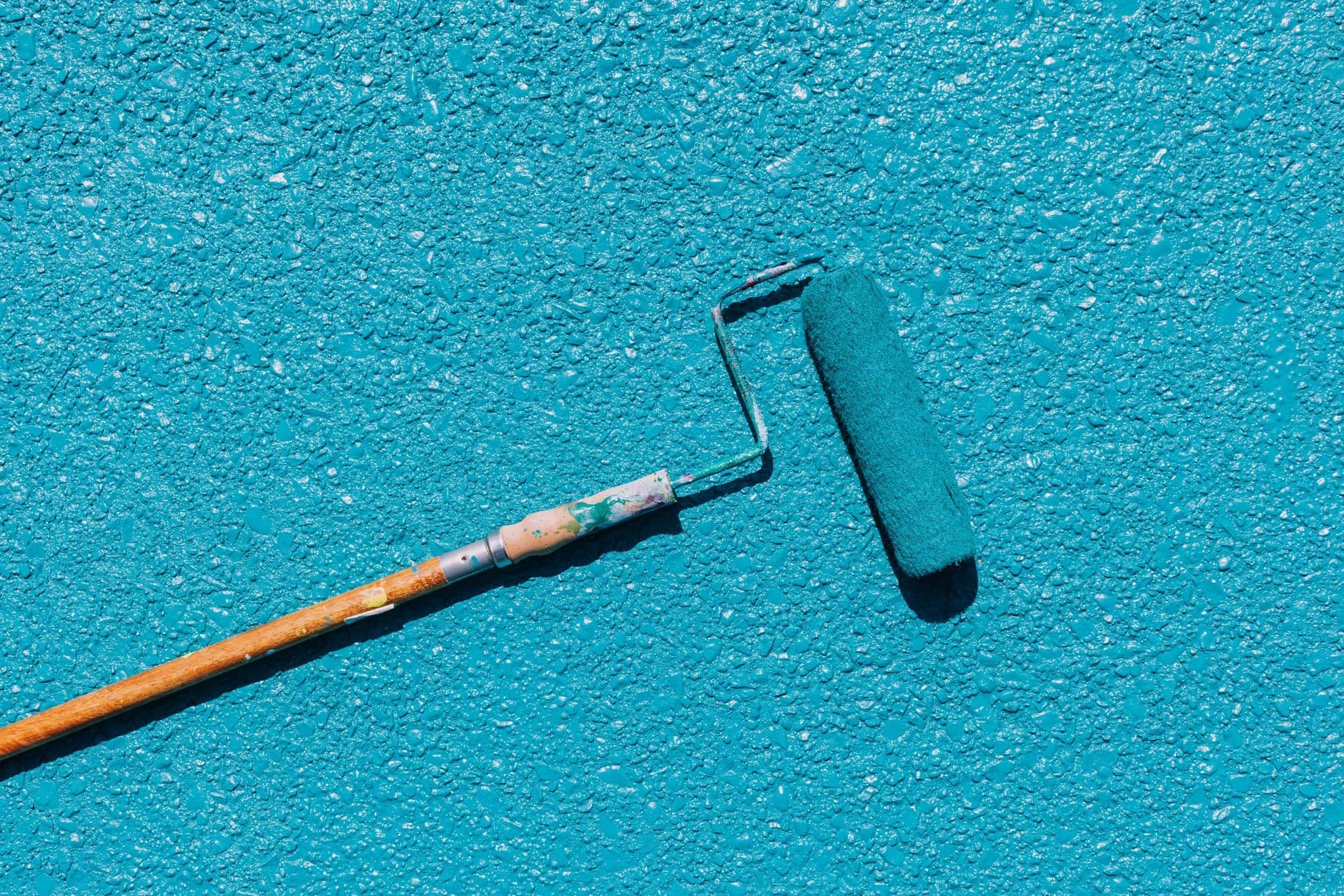 A paint roller resting on a freshly painted textured wall.