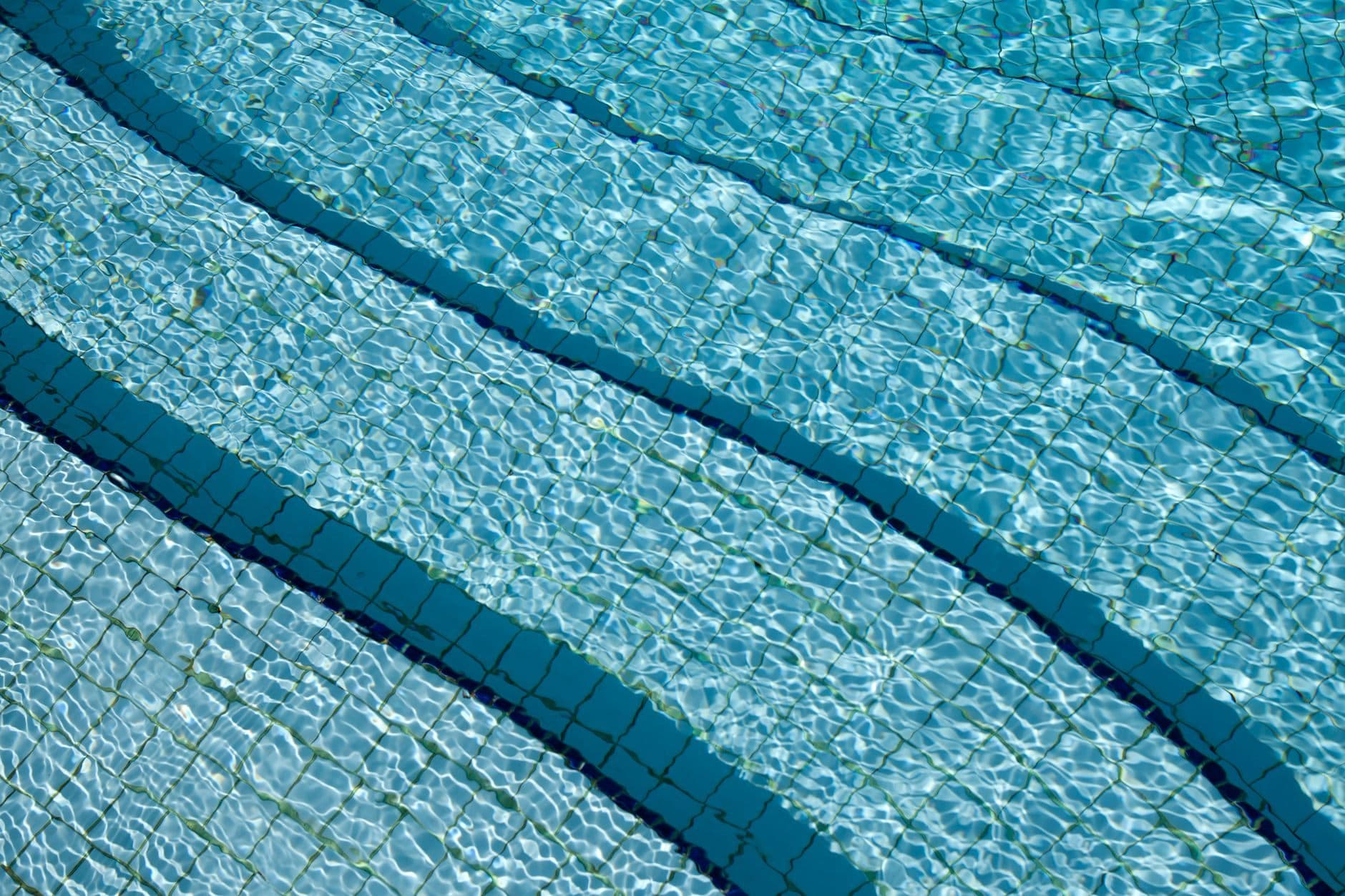Clear pool water over blue tiling, with the darker tiled lines of the pool floor visible beneath.